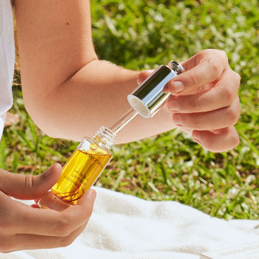 Person holding a dropper bottle outdoors on a grassy background